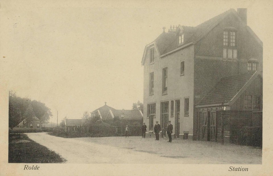 Dezelfde plek van de straatkant, omstreeks 1912: links de zandweg het dorp in, rechts het goederenhuis met de schuifdeuren.